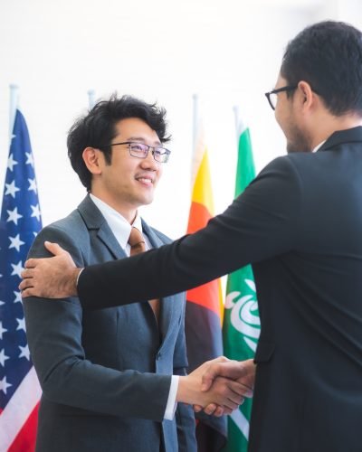 Business people shake hands, international flag background